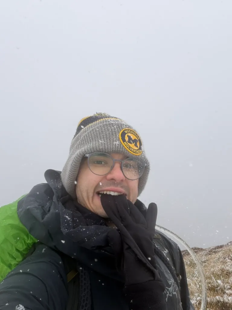 Hiking through falling snow in a Michigan Wolverines beanie