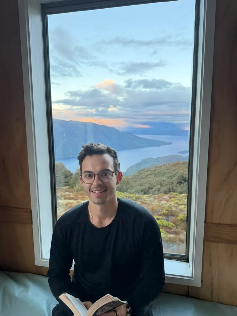 Reading by a window overlooking a lake at sunset